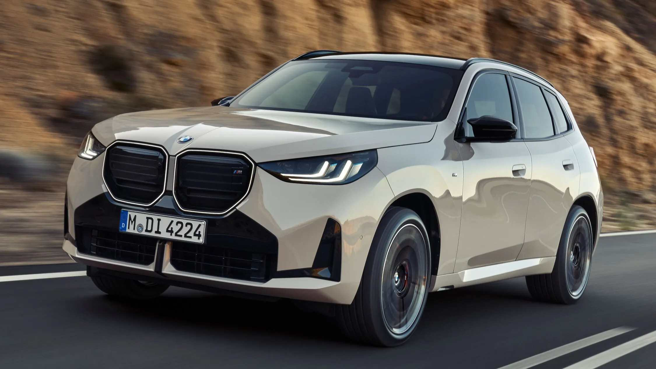 BMW X3 M50 beige en mouvement sur une route