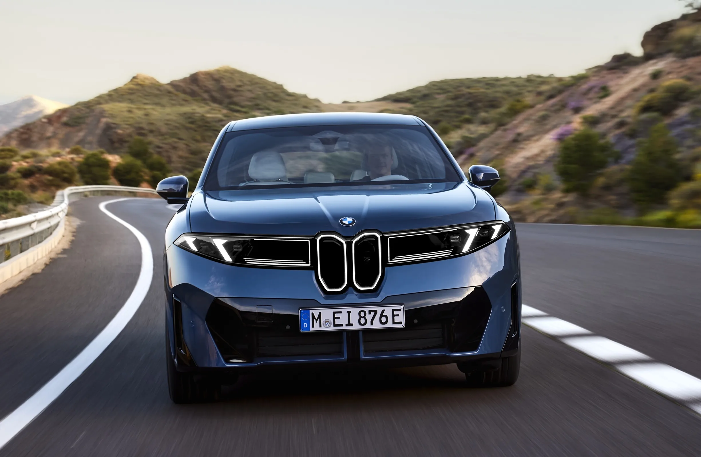 BMW iX3 bleu de face sur une route de montagne